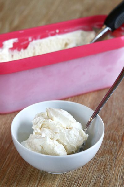 vanilla ice cream in a white bowl with a pink ice cream container behind