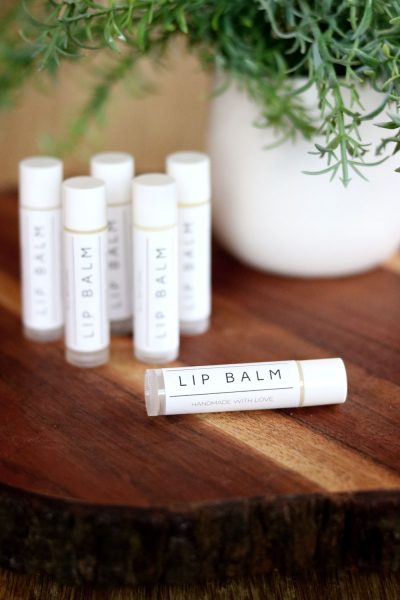 homemade lip balm tubes on a table by a plant