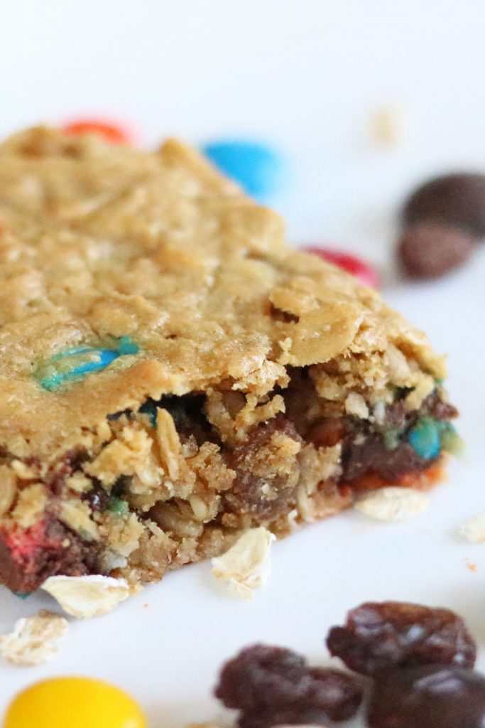 close up photo of no flour monster cookie bars with M&Ms, chocolate chips, raisins and oats around it