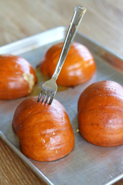sugar pumpkins on a cooking sheet with a fork stuck in